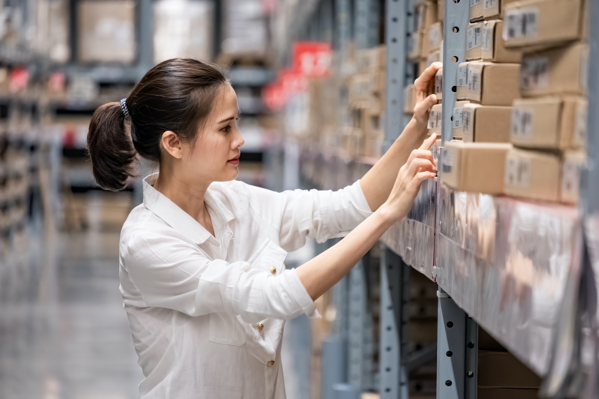Smart Asian young woman happy to work in store warehouse.